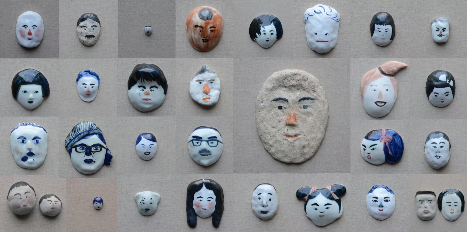 Deng Ying ceramic face studies arranged on linen.
